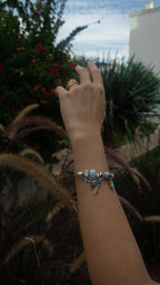 Hand with a bracelet reaching towards plants outdoors