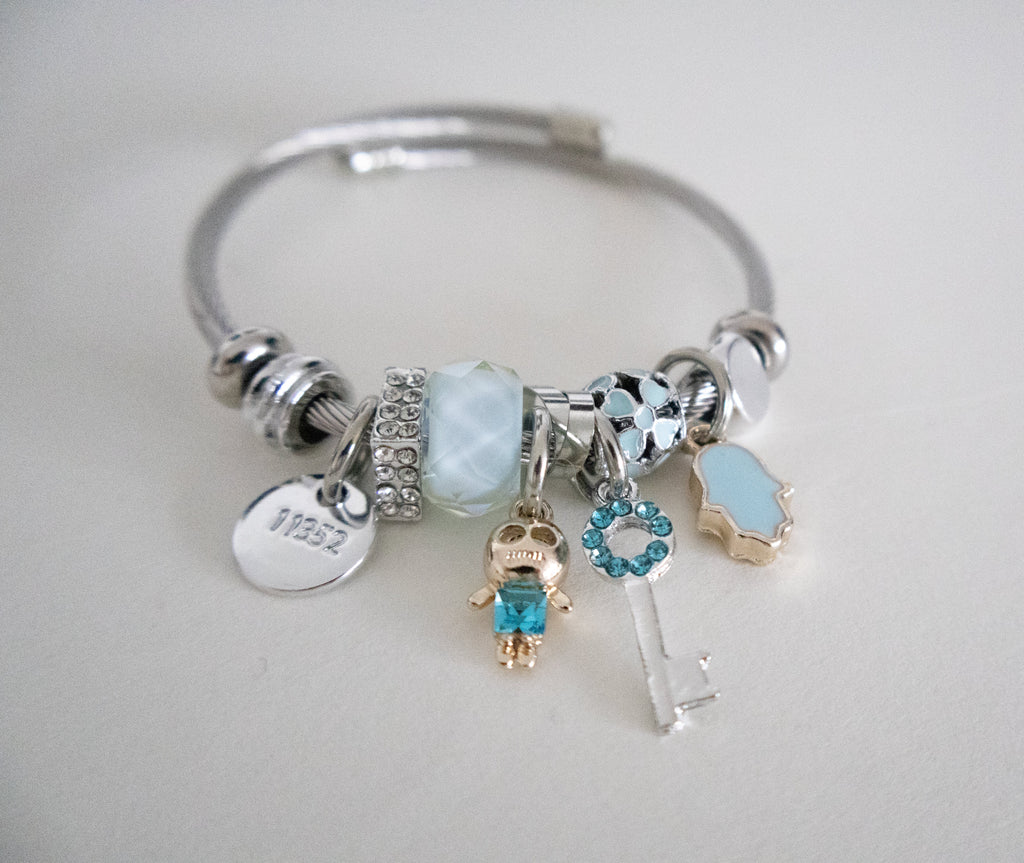Silver bracelet with various charms on a light gray background
