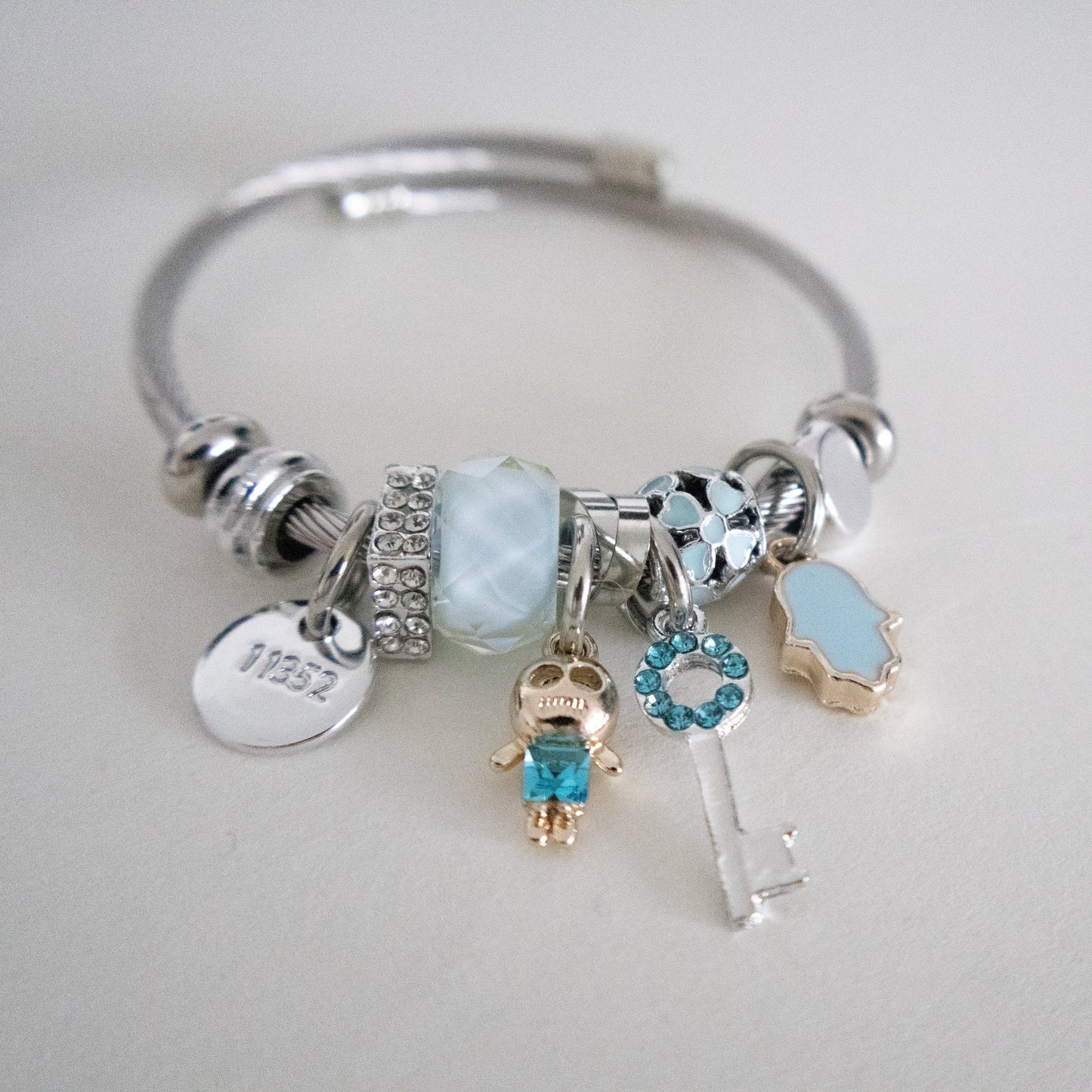 Silver bracelet with various charms on a light gray background