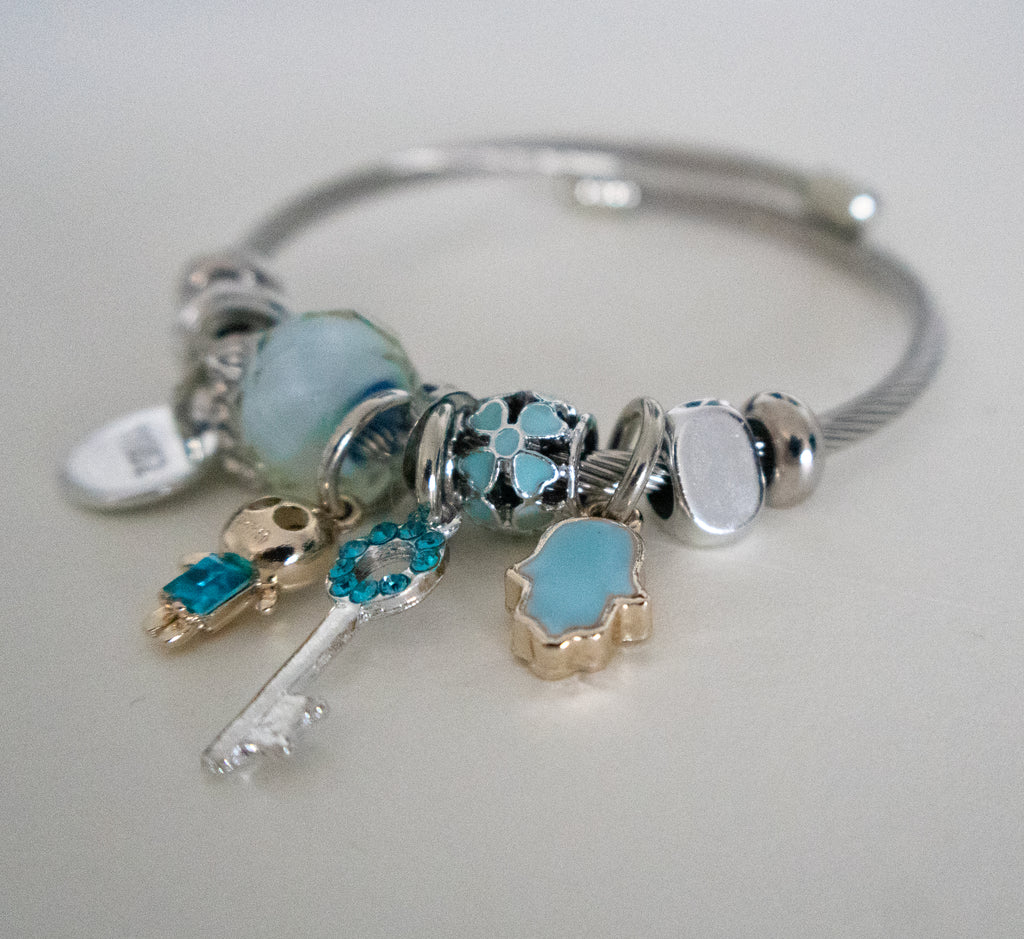 Silver bracelet with various charms on a light gray background