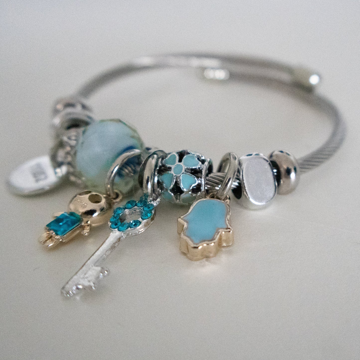 Silver bracelet with various charms on a light gray background