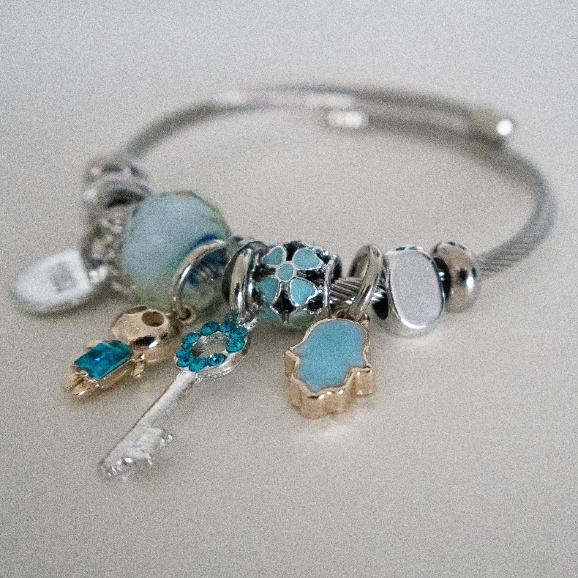 Silver bracelet with various charms on a light gray background