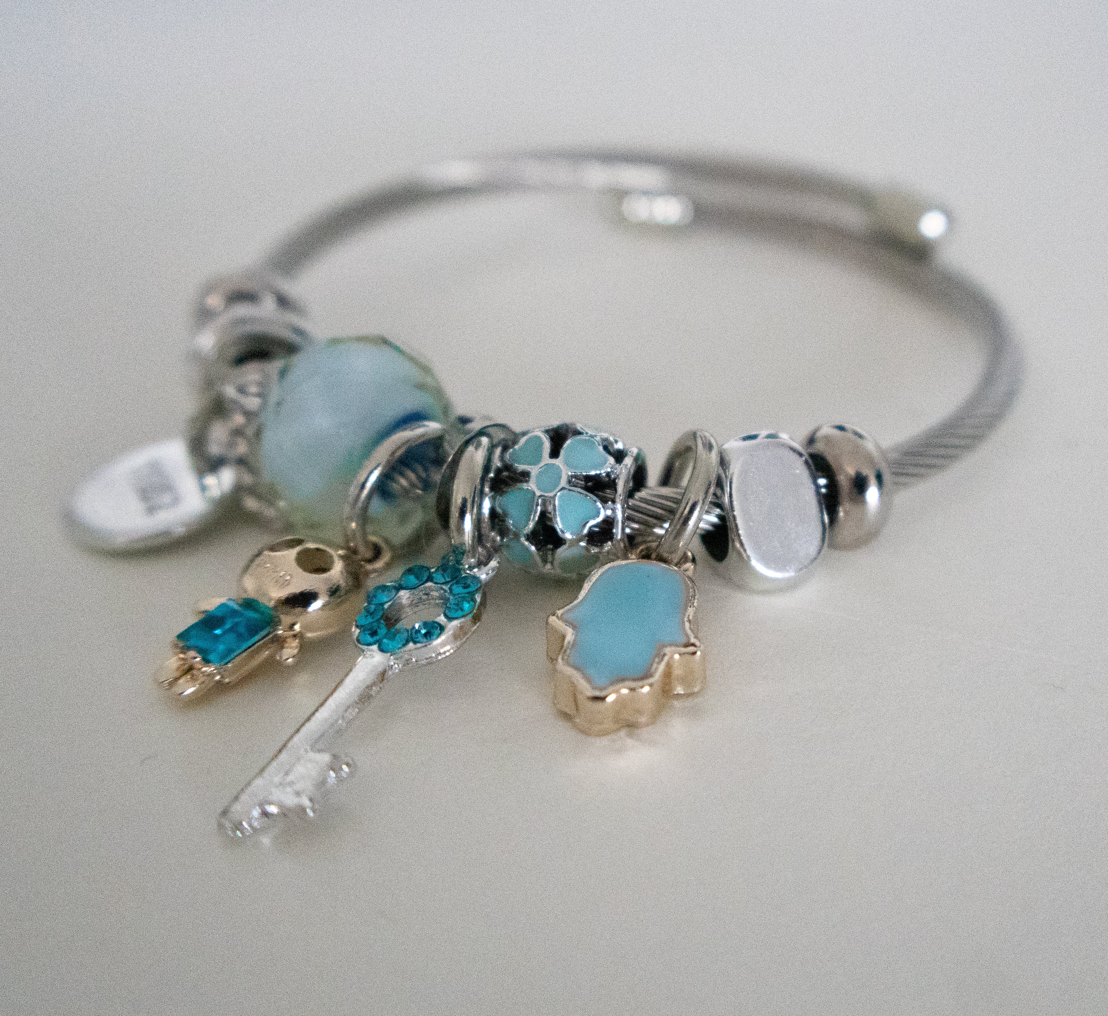 Silver bracelet with various charms on a light gray background