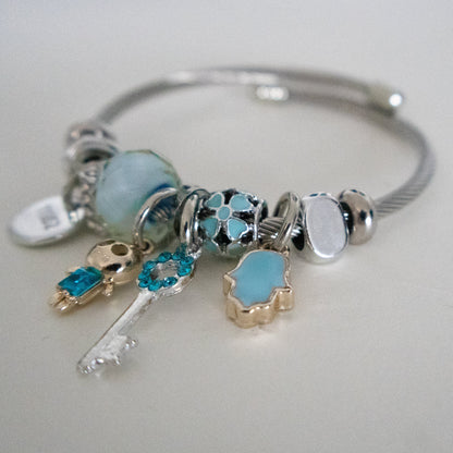 Silver bracelet with various charms on a light gray background