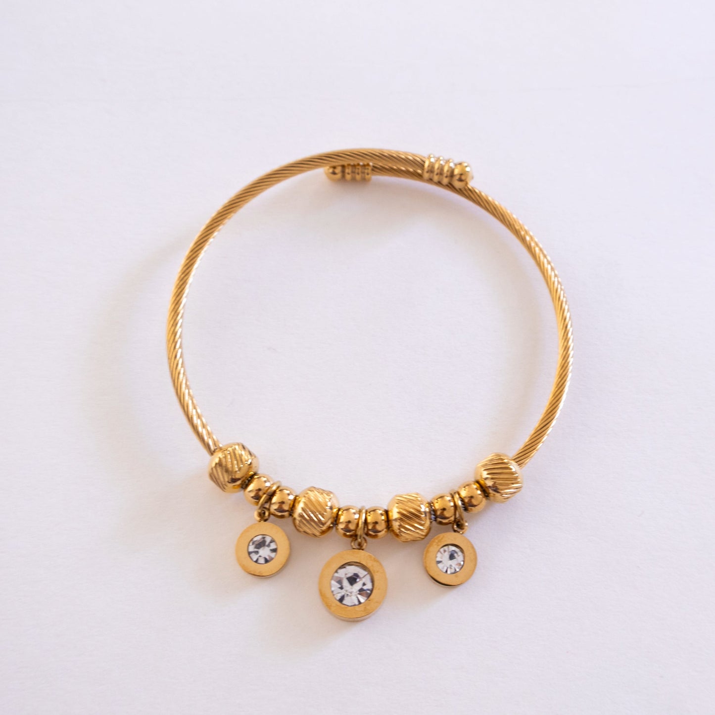 Gold bracelet with beads and crystals on a light gray background