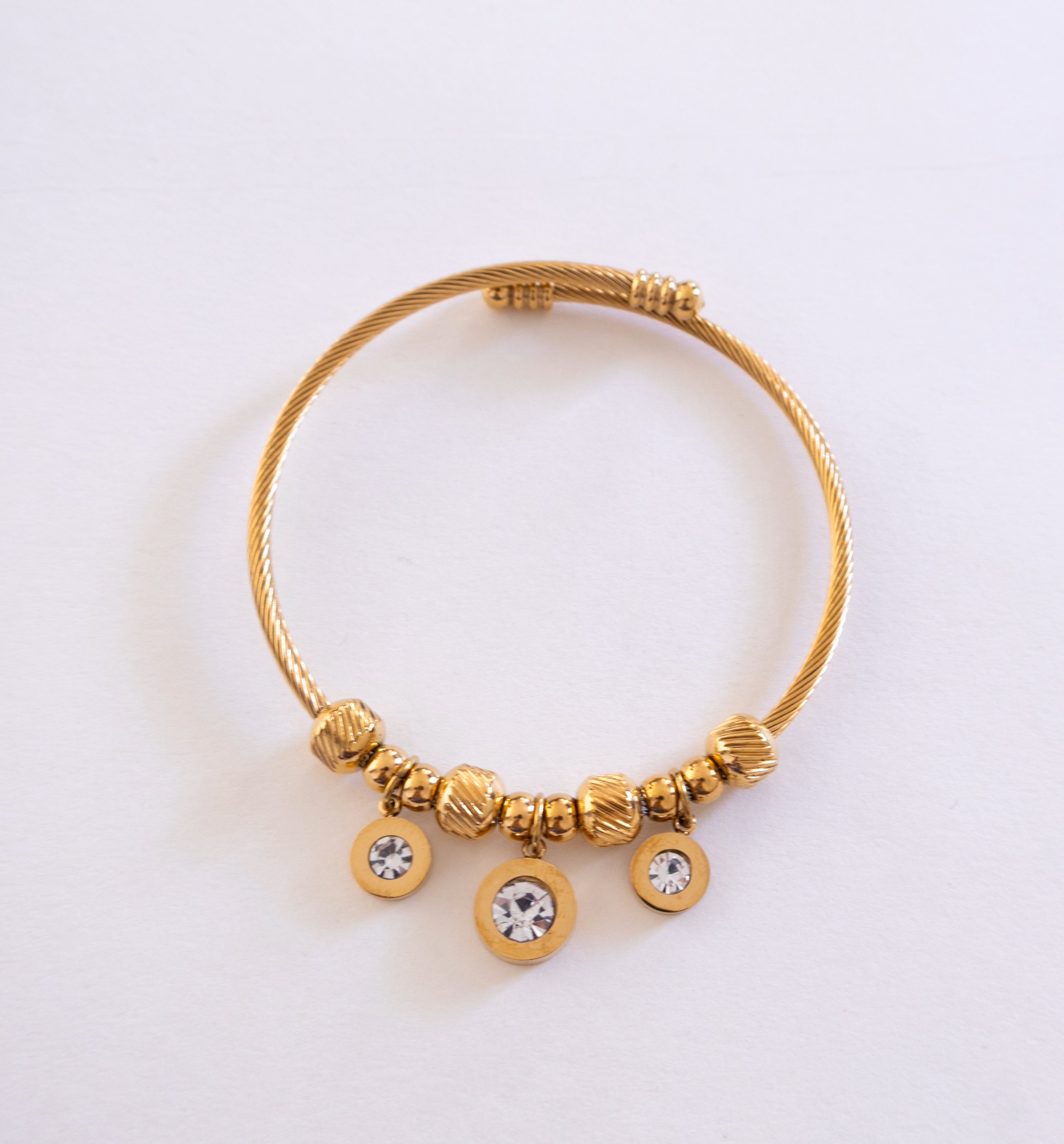 Gold bracelet with beads and crystals on a light gray background