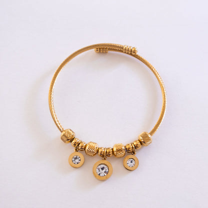 Gold bracelet with beads and crystals on a light gray background