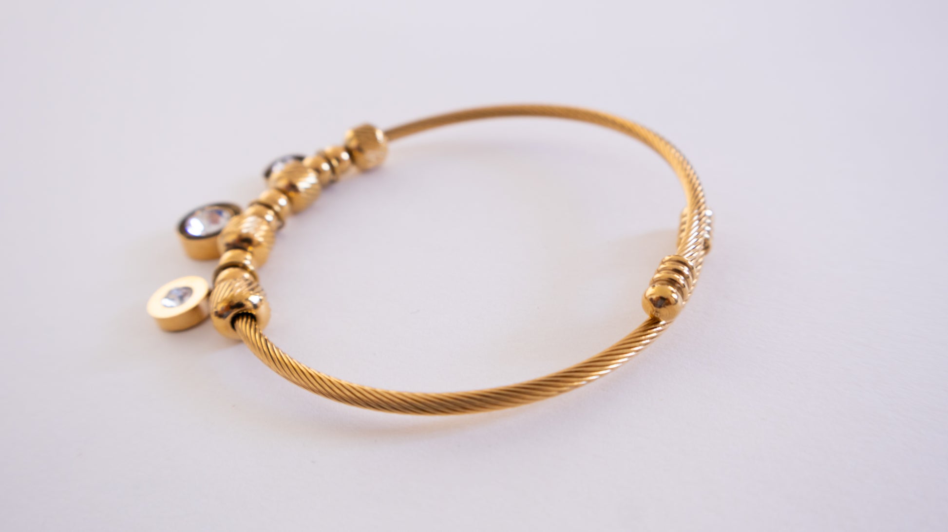 Gold bracelet with beads on a light gray background