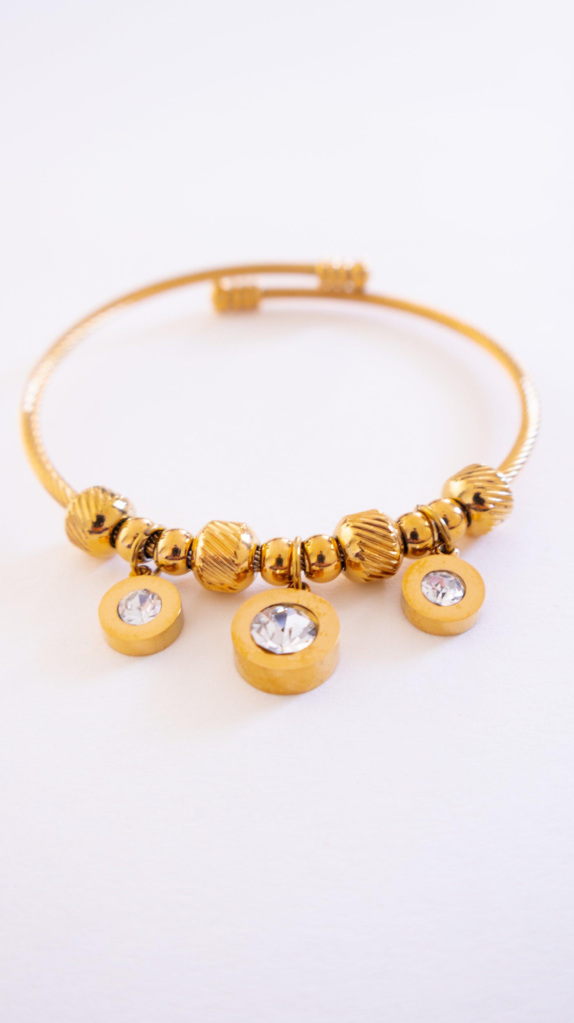 Gold bracelet with beads and crystals on a white background