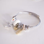 Silver bracelet with various charms on a light gray background