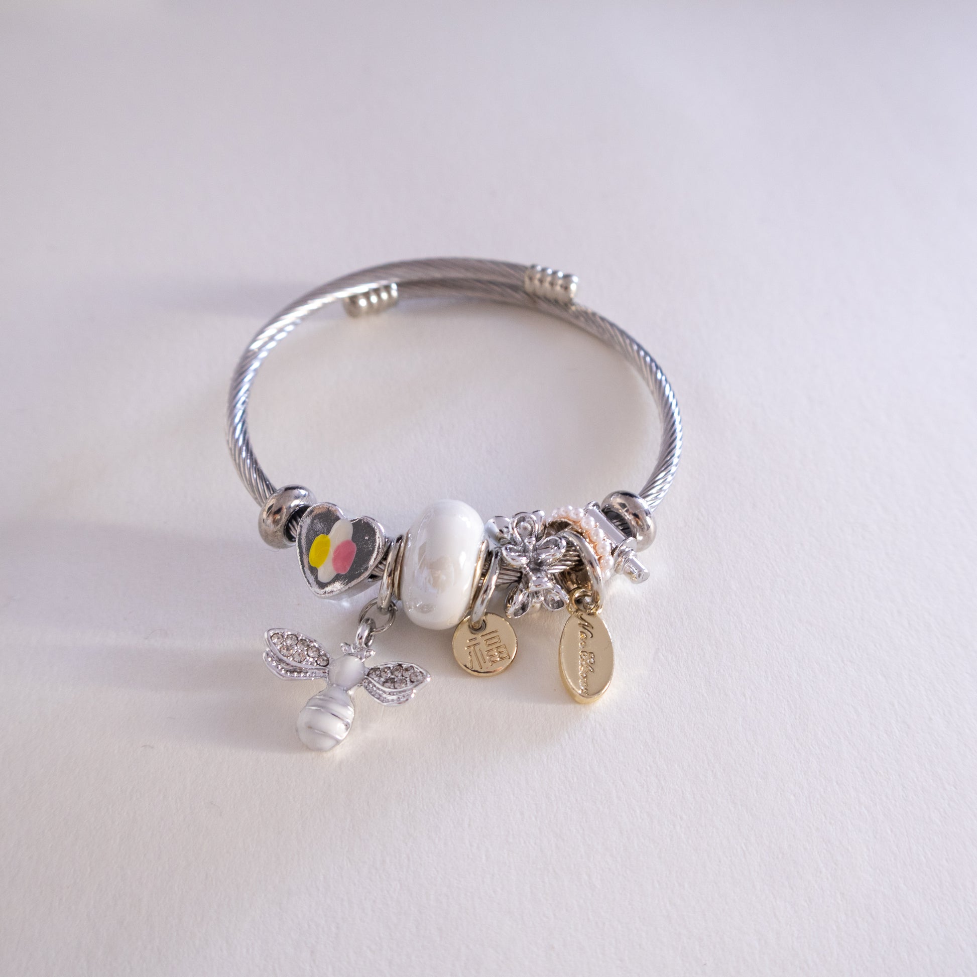 Silver bracelet with various charms on a light gray background