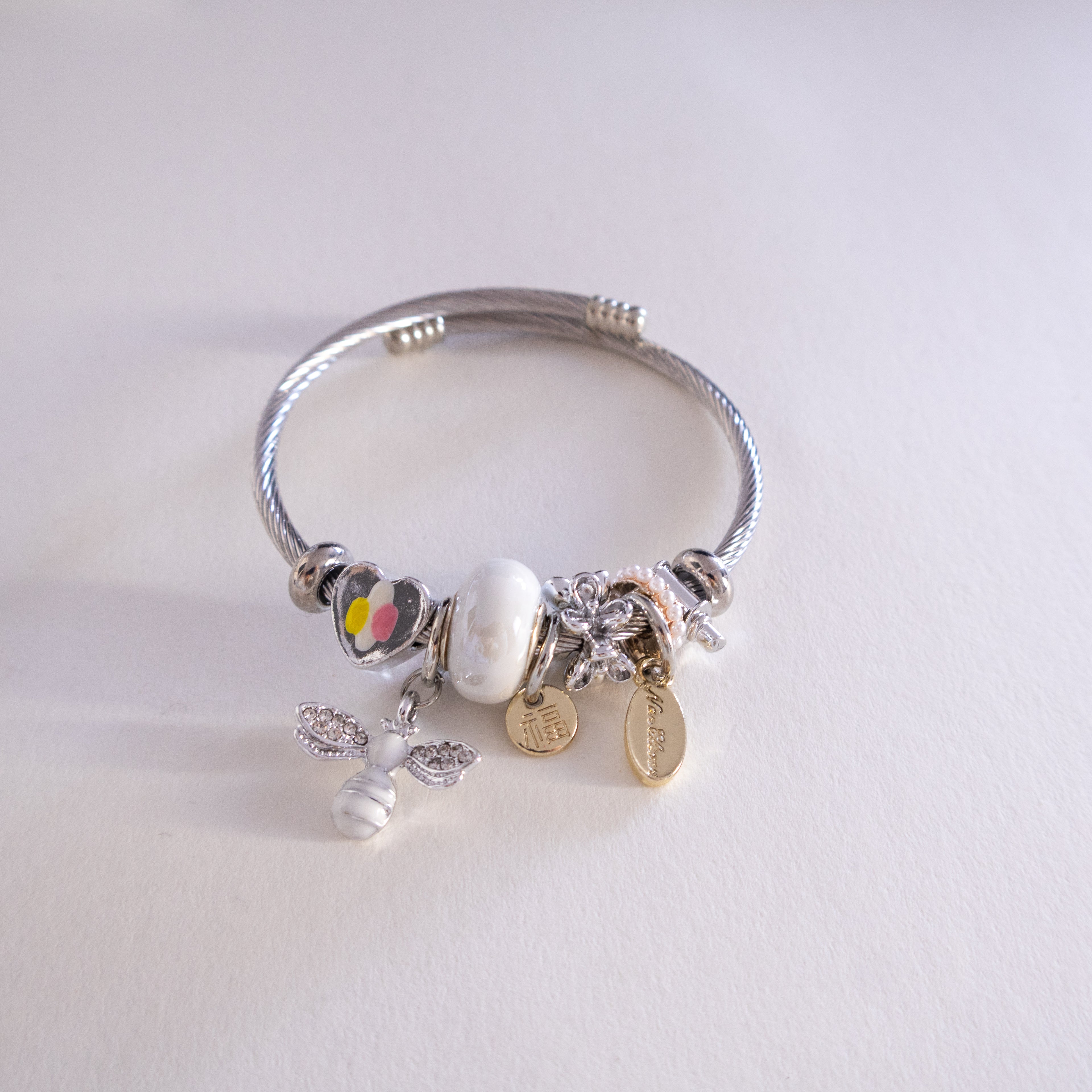 Silver bracelet with various charms on a light gray background