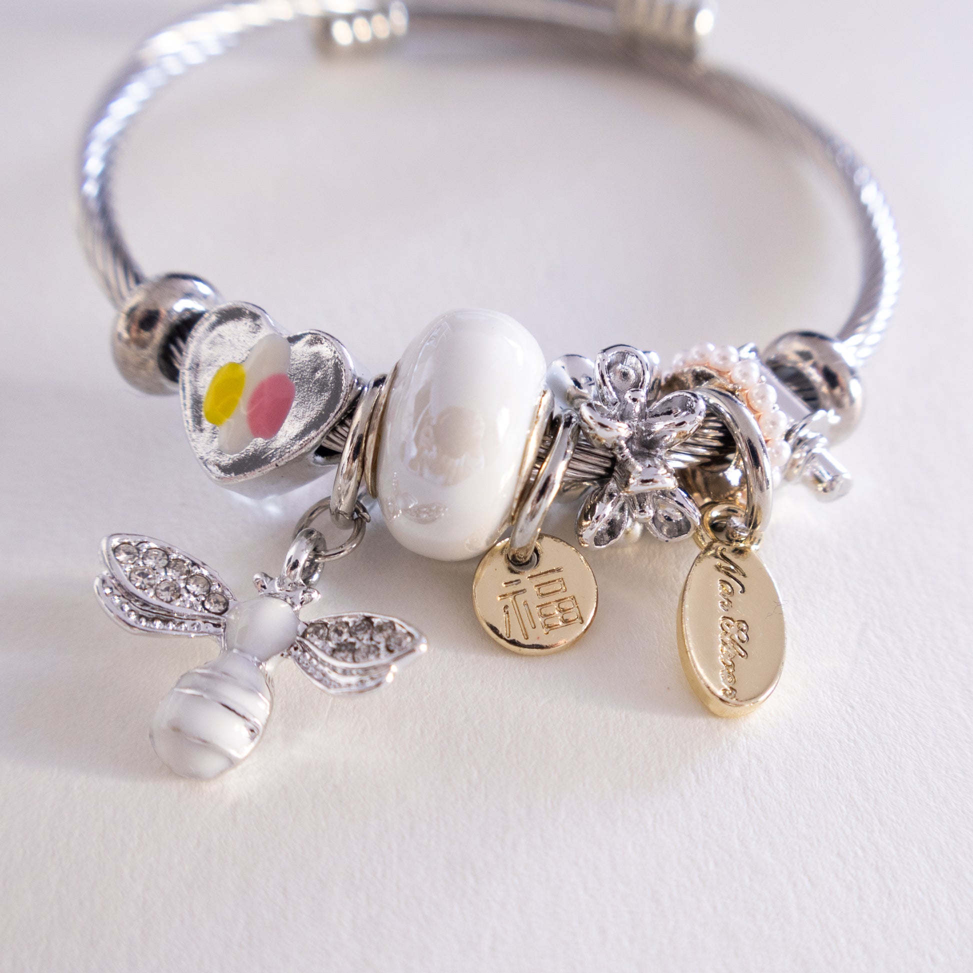 Silver bracelet with various charms on a white background