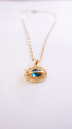 Gold necklace with a blue eye pendant on a white background