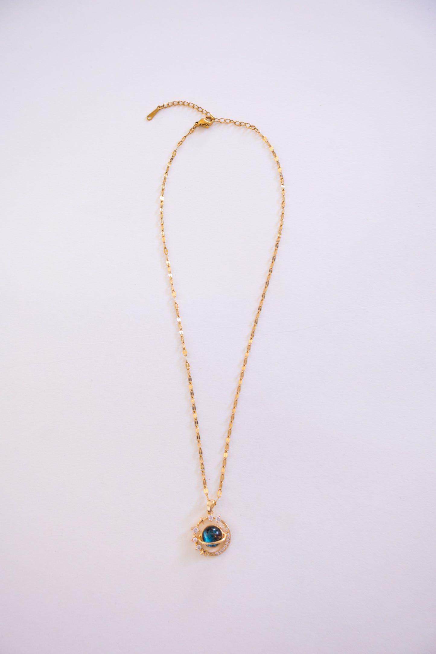 Gold necklace with a pendant on a light purple background