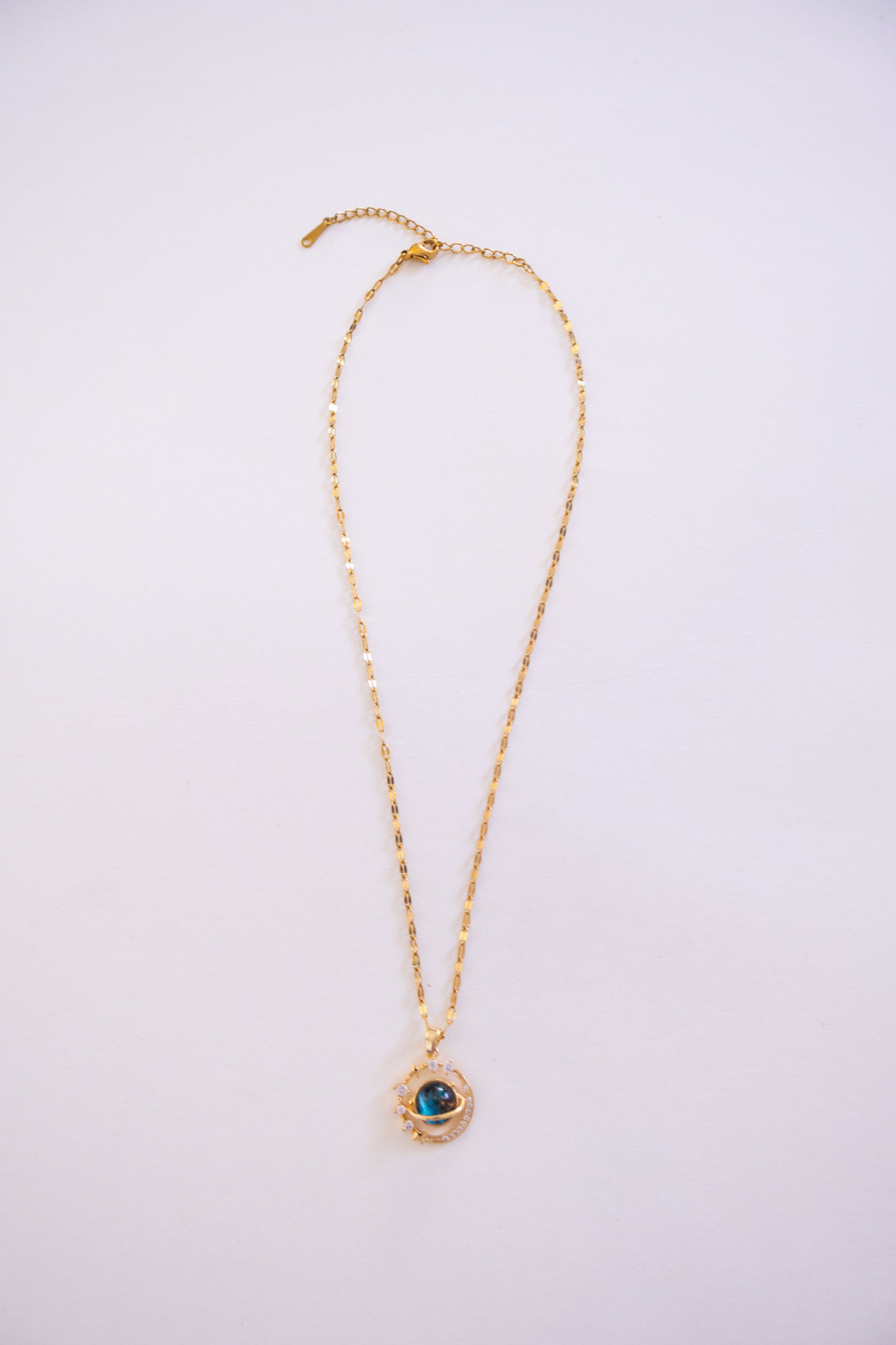 Gold necklace with a pendant on a light purple background