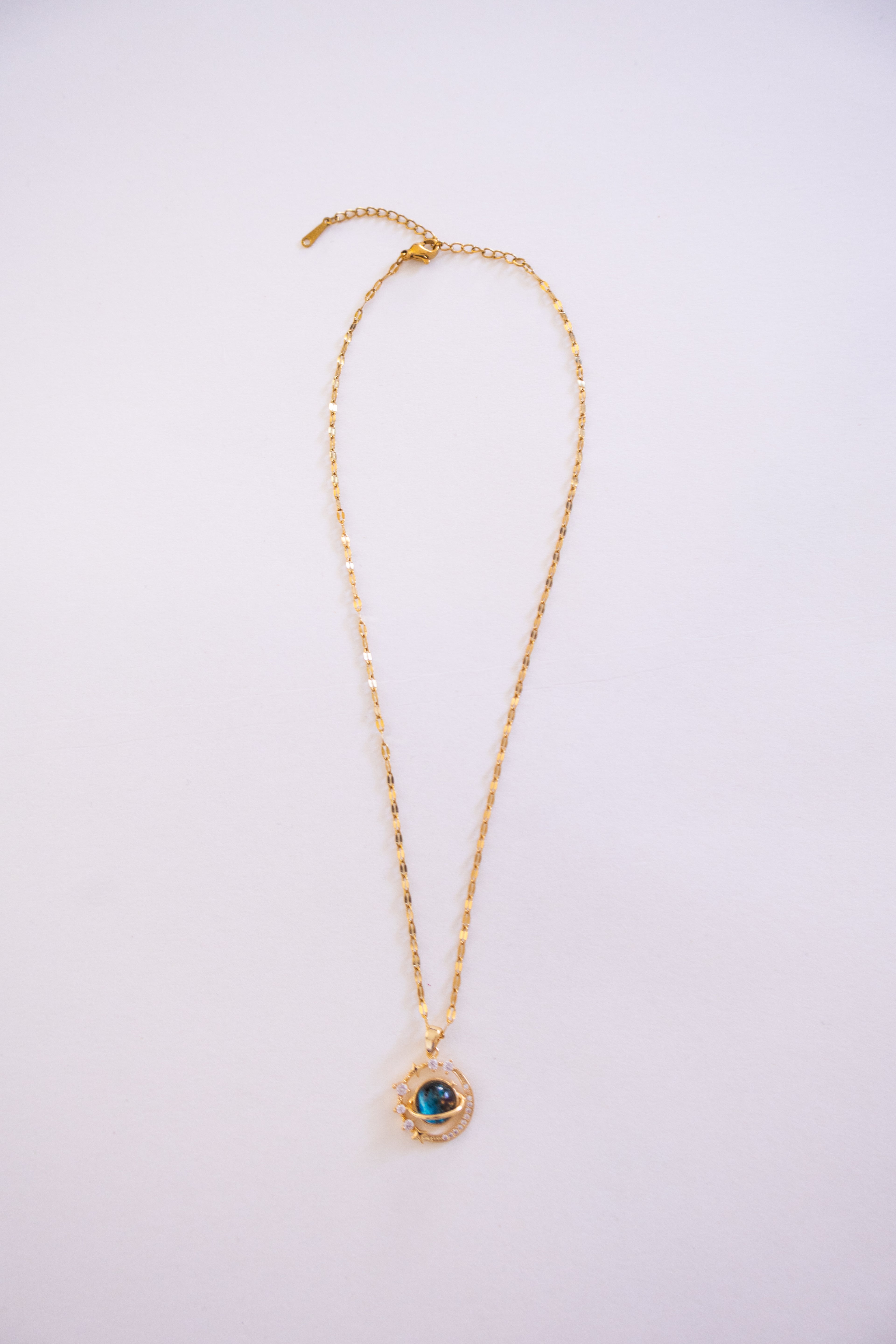 Gold necklace with a pendant on a light purple background