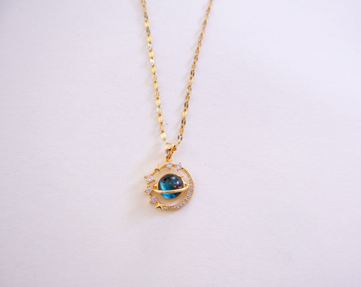 Gold necklace with a blue gemstone pendant on a white background