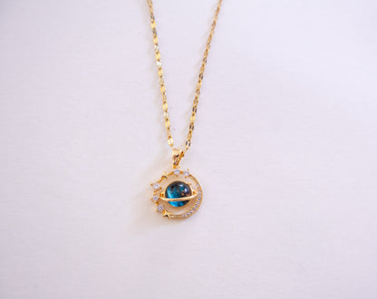 Gold necklace with a blue gemstone pendant on a white background