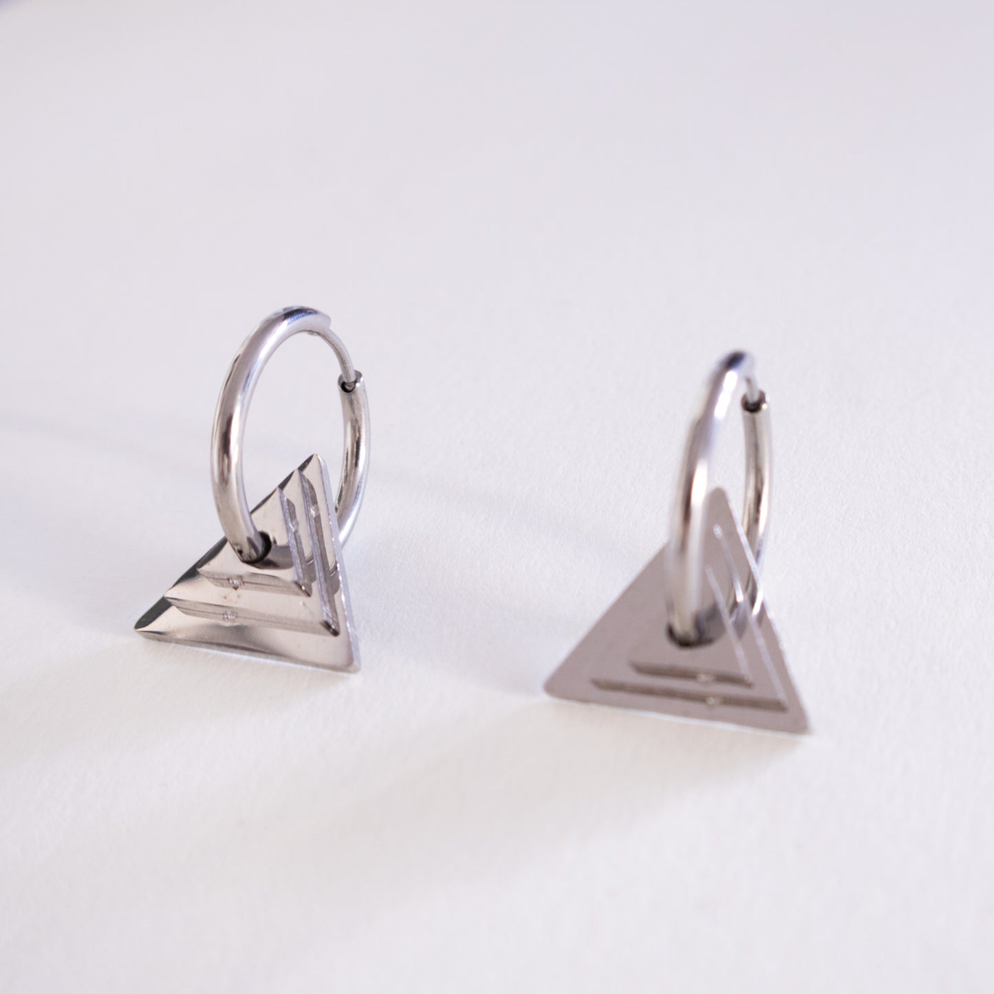 Pair of silver triangle earrings on a light gray background