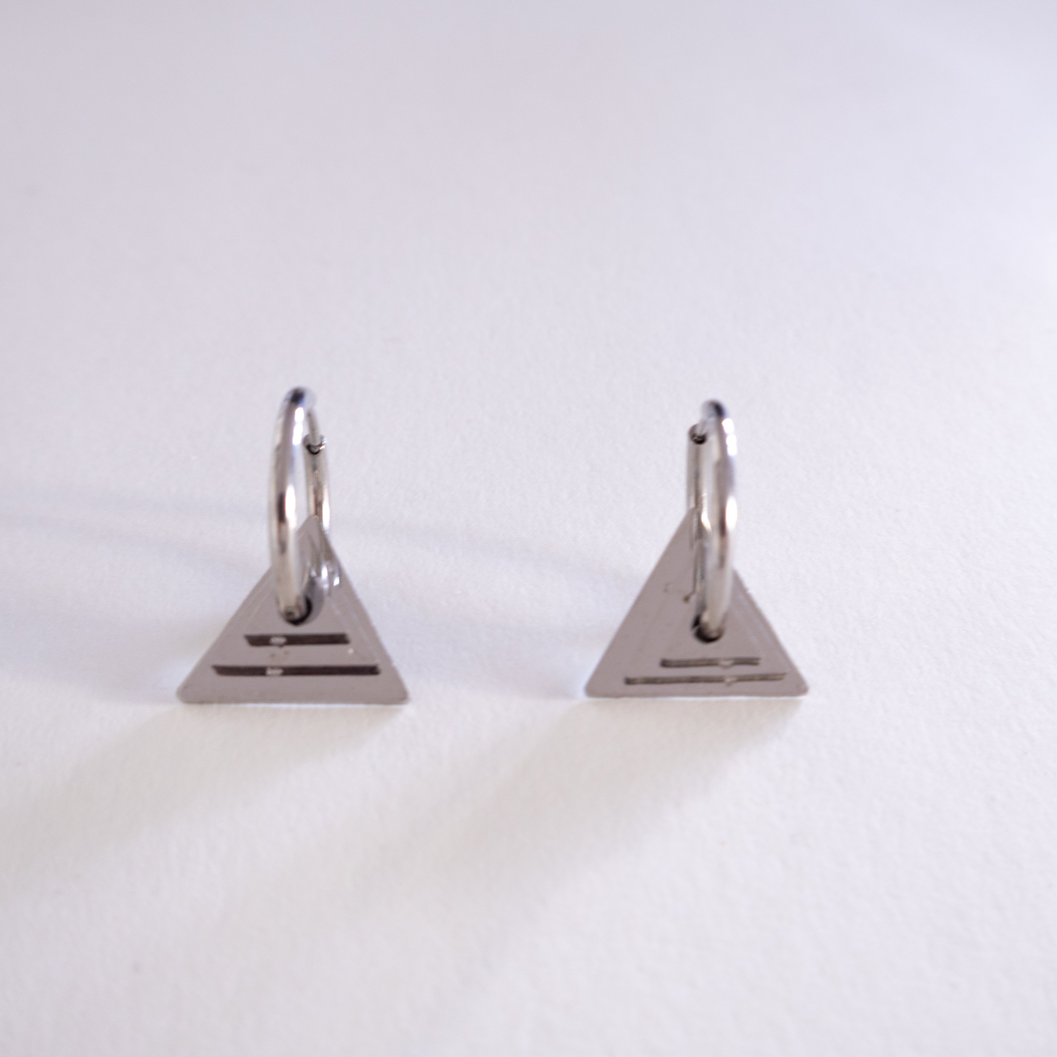 Pair of silver triangle-shaped earrings on a white background
