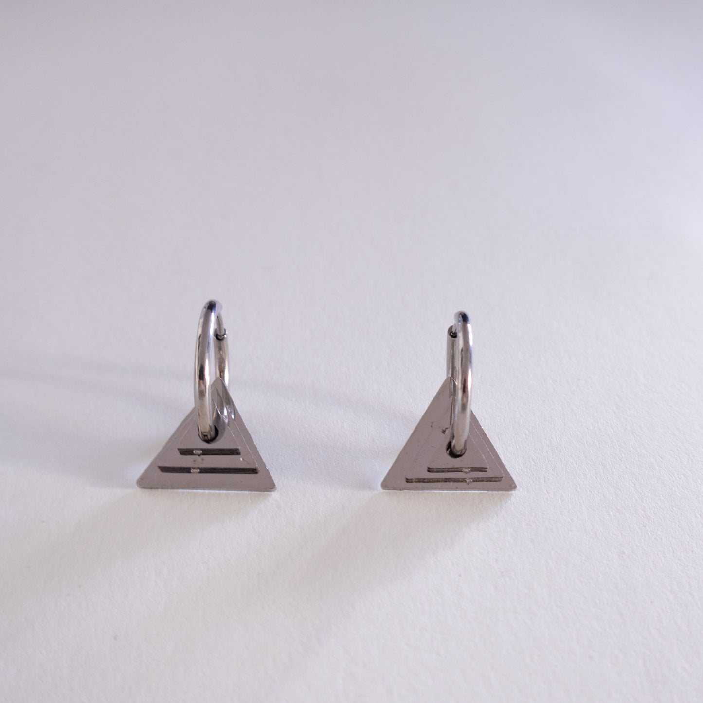 Pair of triangle-shaped earrings on a light gray background