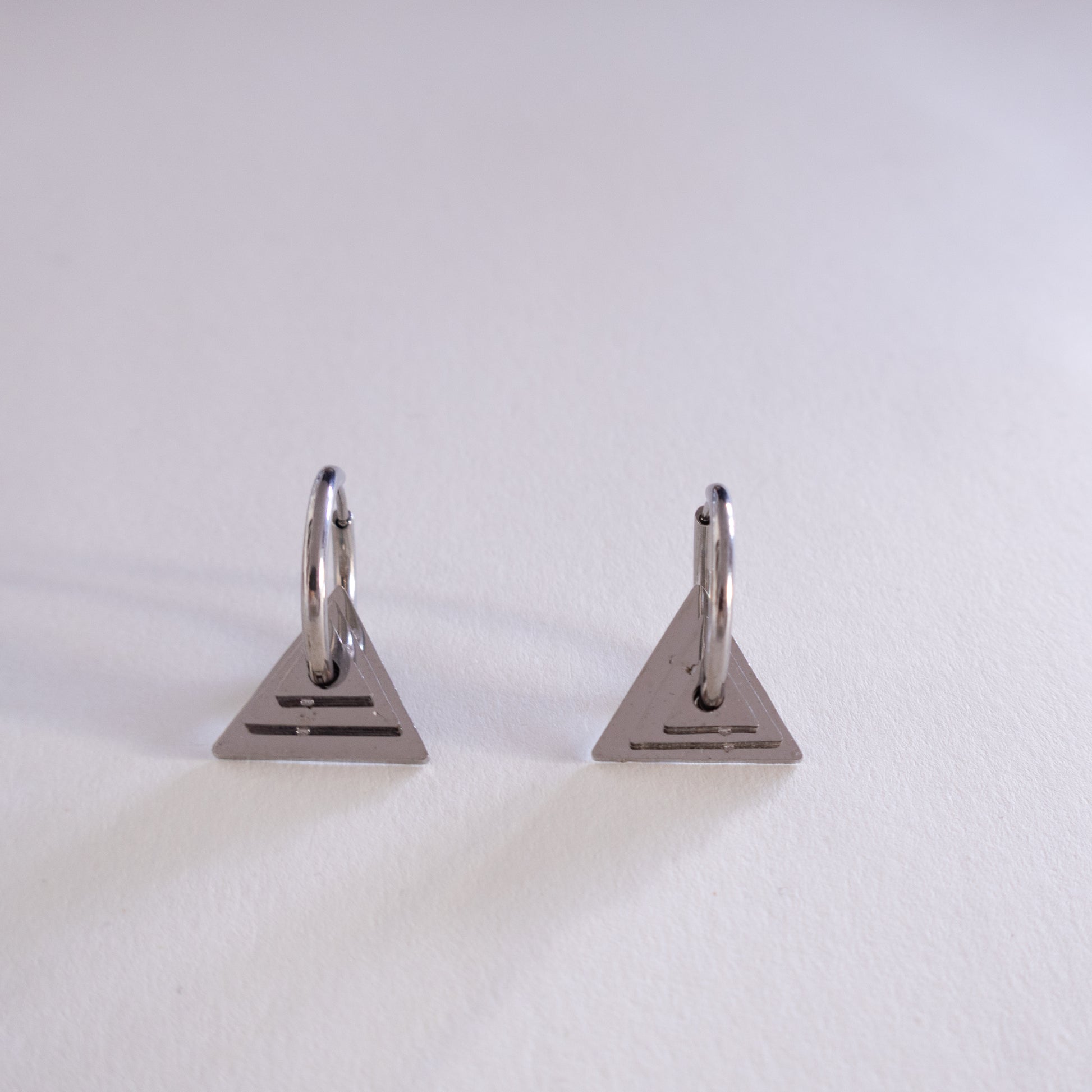 Pair of triangle-shaped earrings on a light gray background