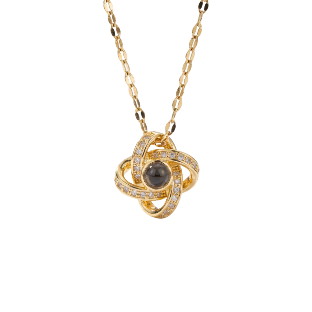 Gold necklace with a central black gemstone and diamond accents on a white background