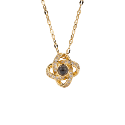 Gold necklace with a central black gemstone and diamond accents on a white background