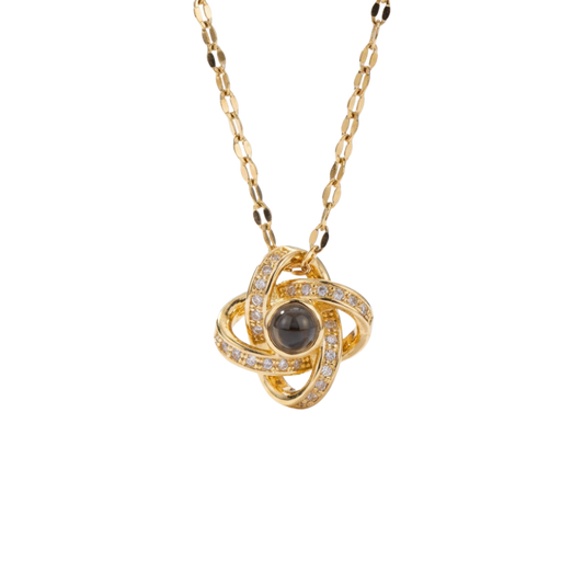 Gold necklace with a central black gemstone and diamond accents on a white background