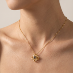 Gold necklace with a intricate pendant on a person's neck against a neutral background