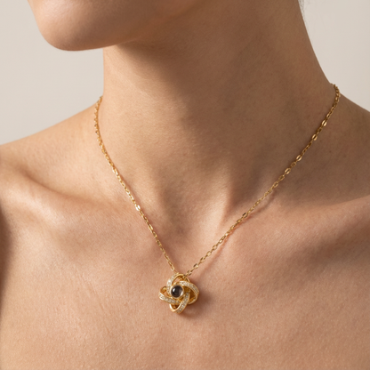 Gold necklace with a intricate pendant on a person's neck against a neutral background
