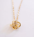 Gold necklace with a heart-shaped pendant on a light background