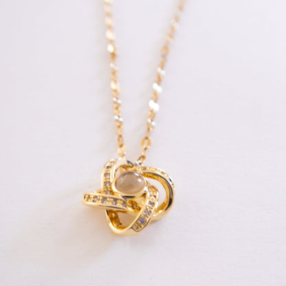 Gold necklace with a heart-shaped pendant on a light background