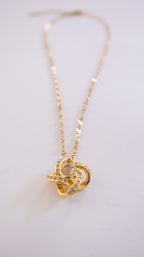 Gold necklace with a intricate pendant on a light gray background