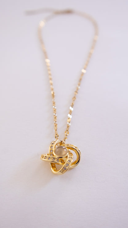 Gold necklace with a intricate pendant on a light gray background