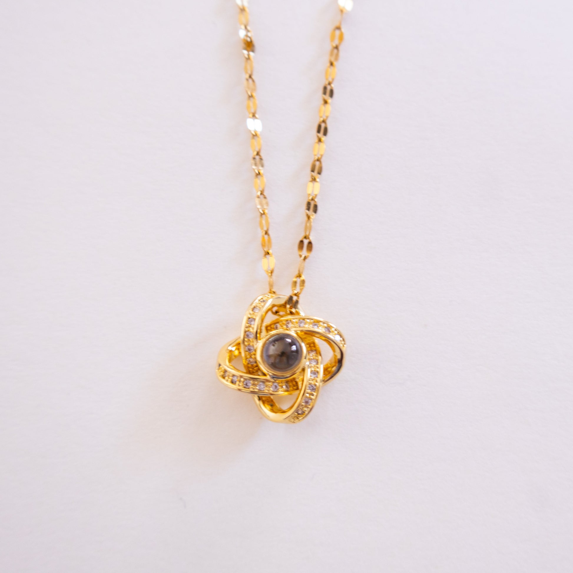Gold necklace with a pendant on a light gray background