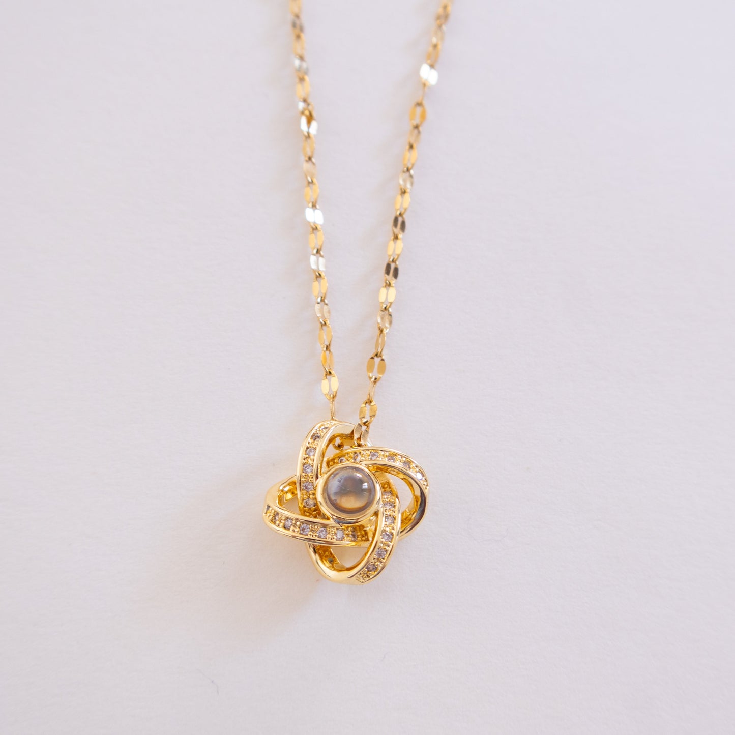 Gold necklace with a heart-shaped pendant on a light gray background