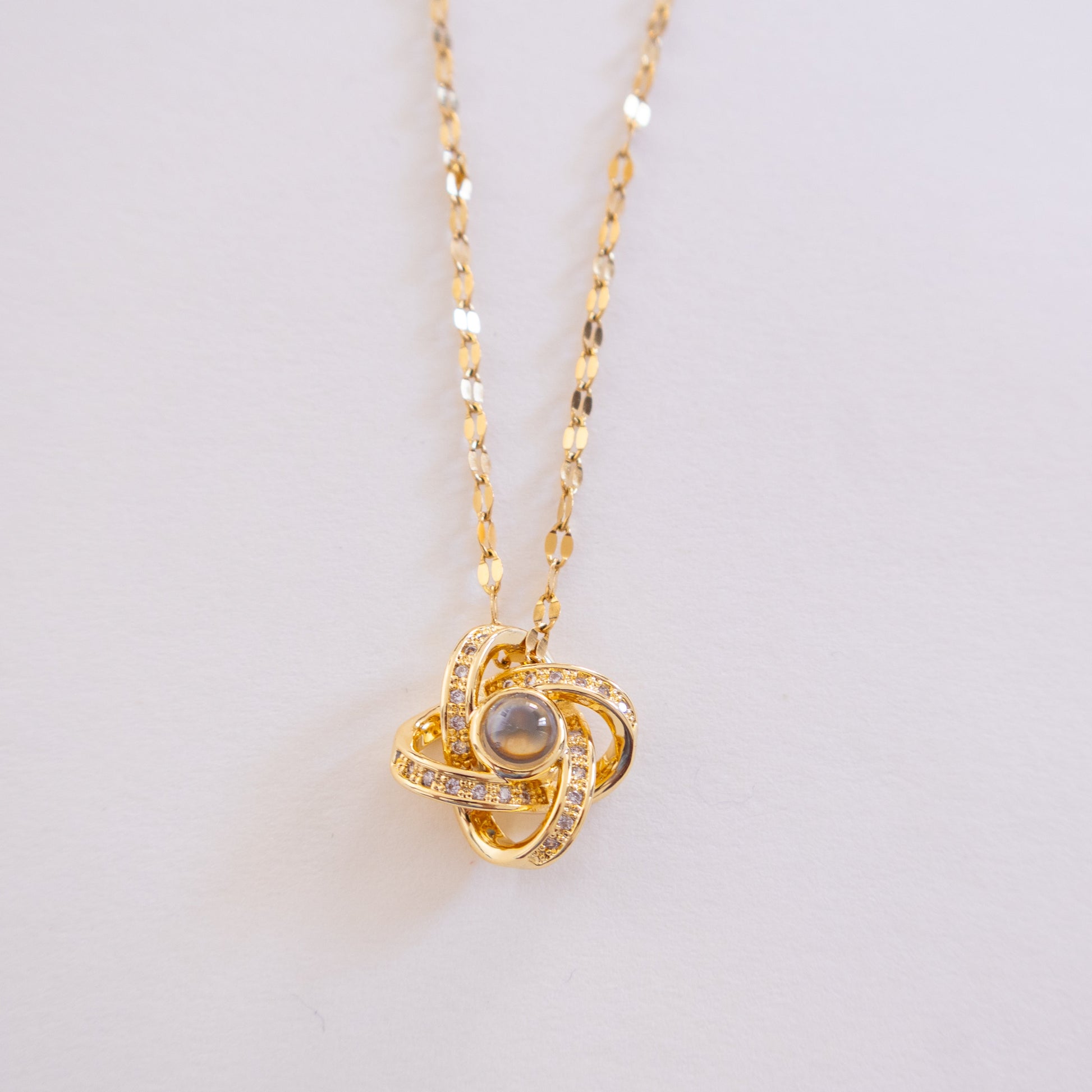 Gold necklace with a heart-shaped pendant on a light gray background