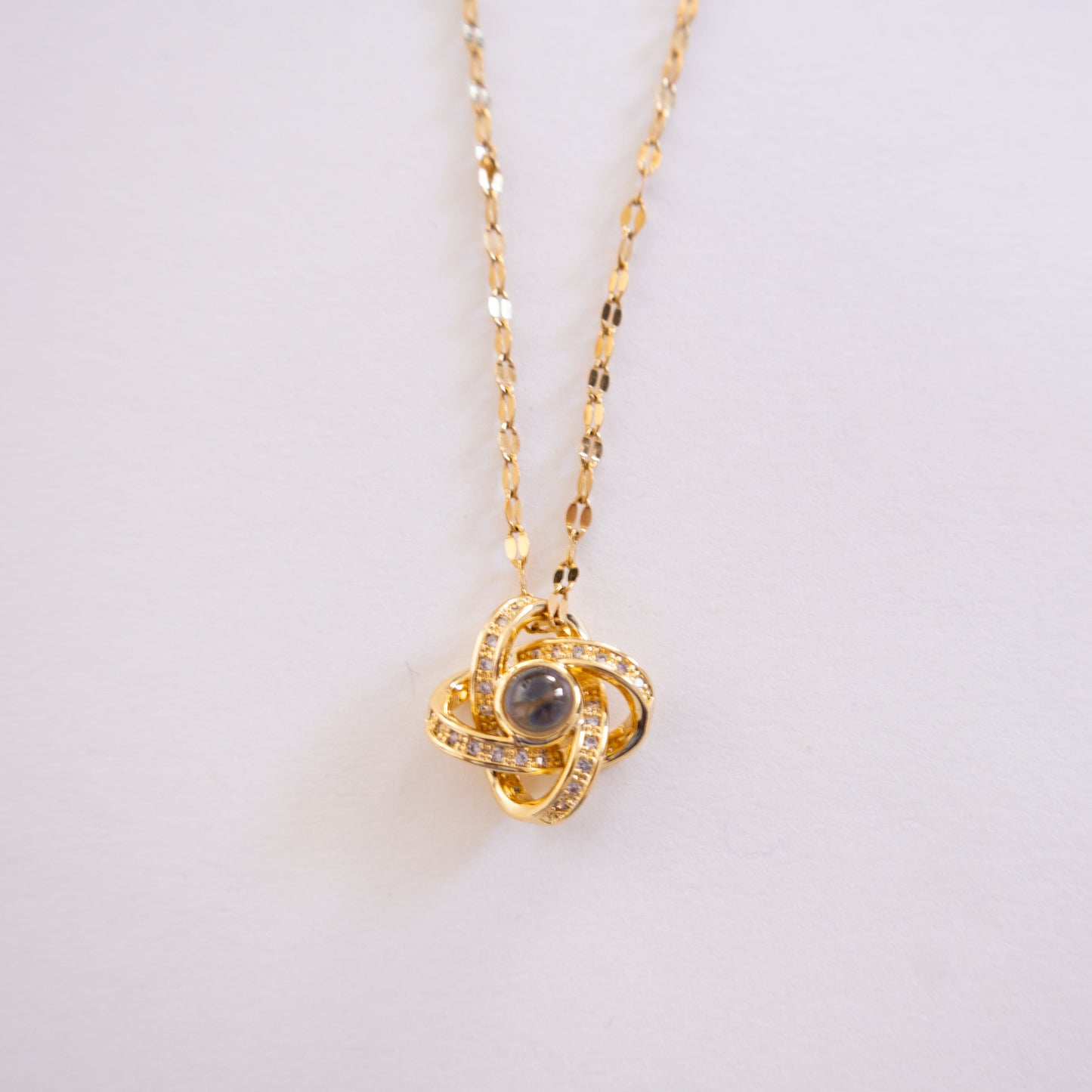 Gold necklace with a pendant on a light gray background