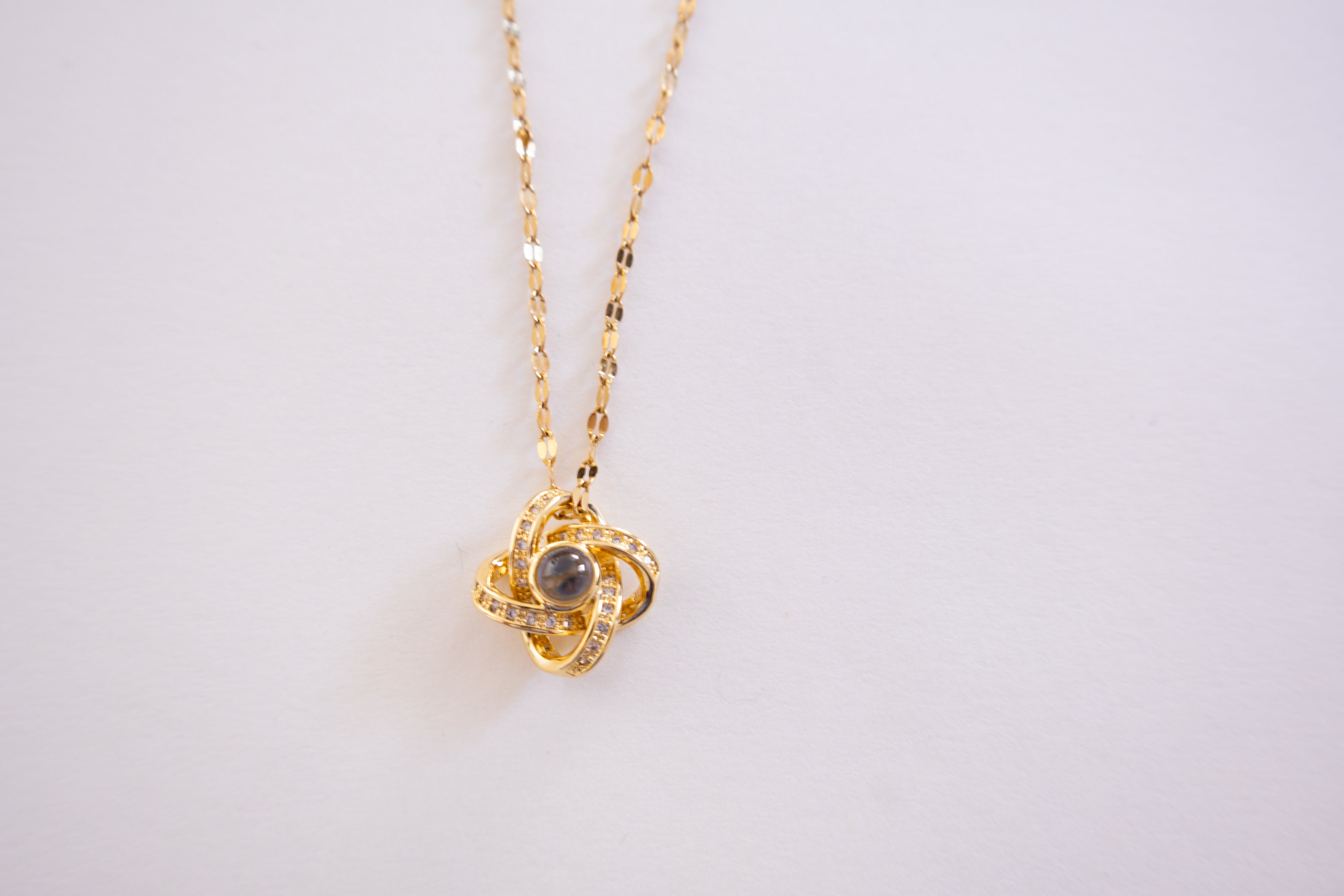 Gold necklace with a pendant on a light gray background