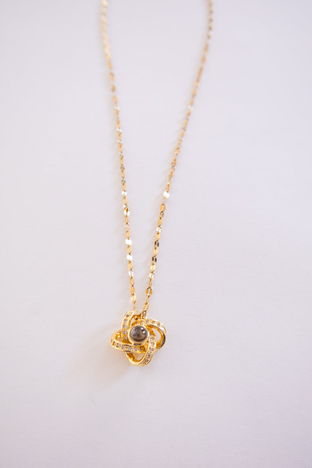 Gold necklace with a pendant on a light gray background