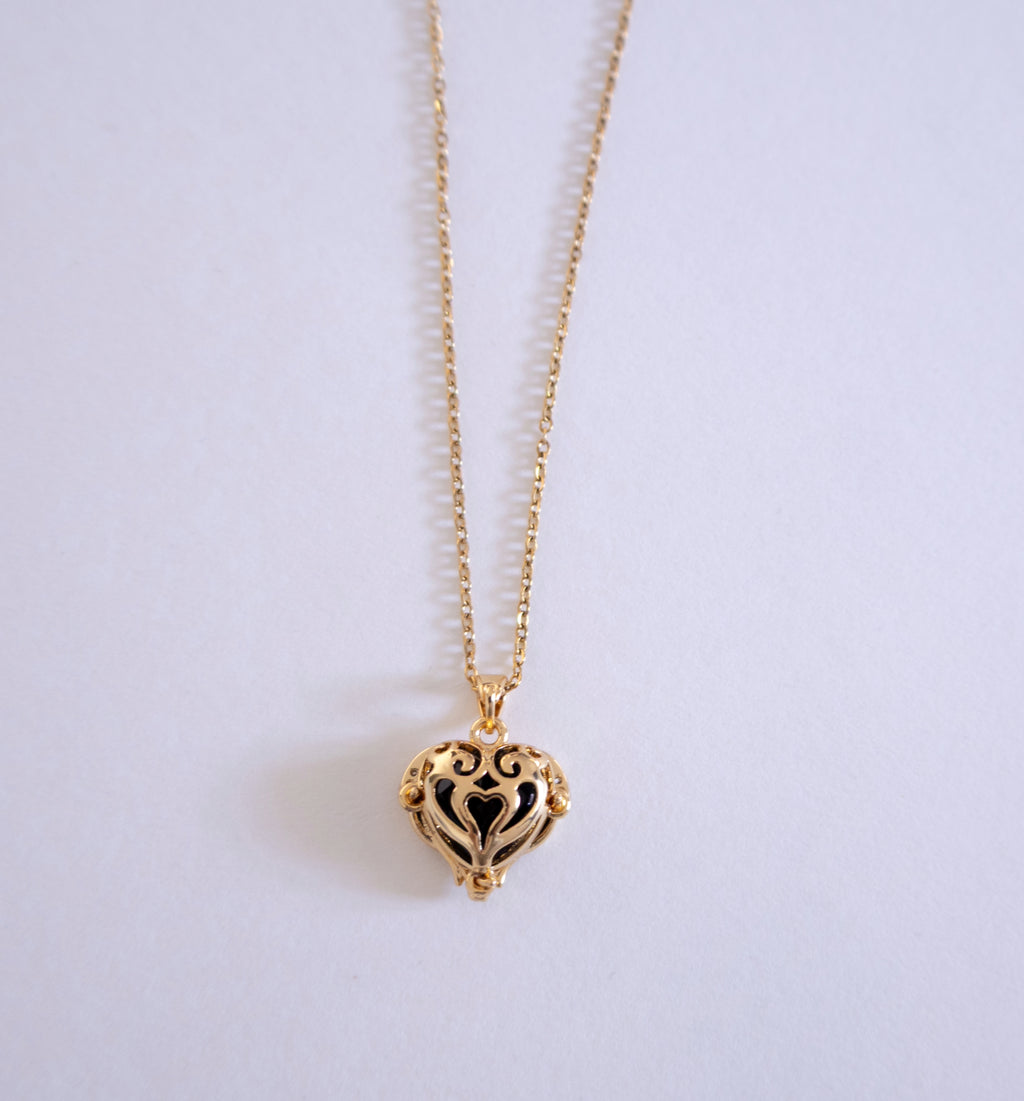 Gold heart-shaped necklace on a light gray background