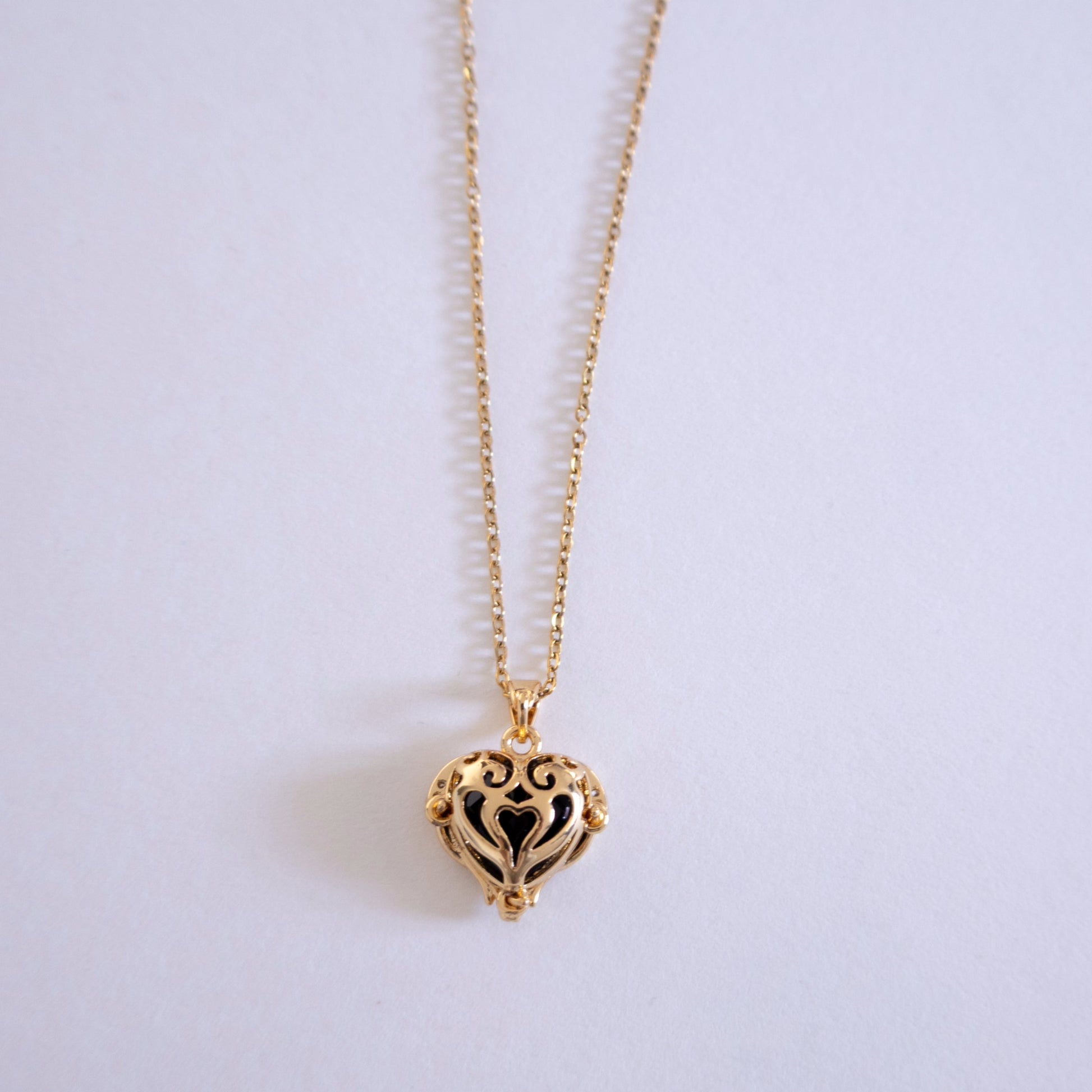 Gold heart-shaped necklace on a light gray background