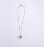 Gold necklace with a heart-shaped pendant on a light purple background