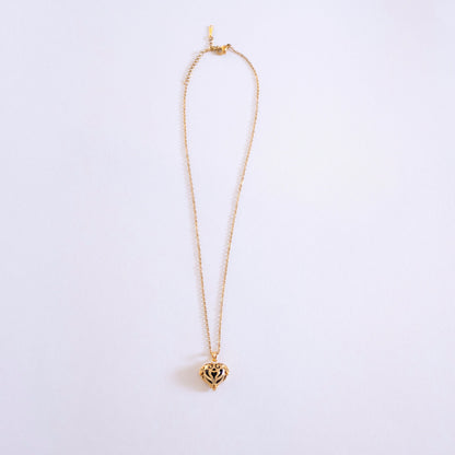 Gold necklace with a heart-shaped pendant on a light purple background