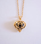 Gold heart-shaped necklace with black interior on a light gray background