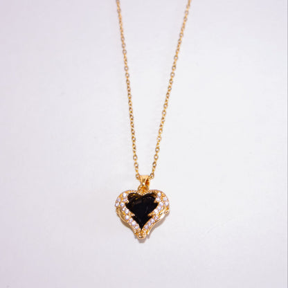 Heart-shaped pendant necklace with black stone on a white background