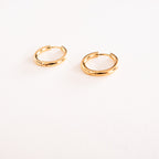 Two gold hoop earrings on a white background