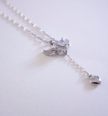 Silver necklace with a heart pendant on a light gray background